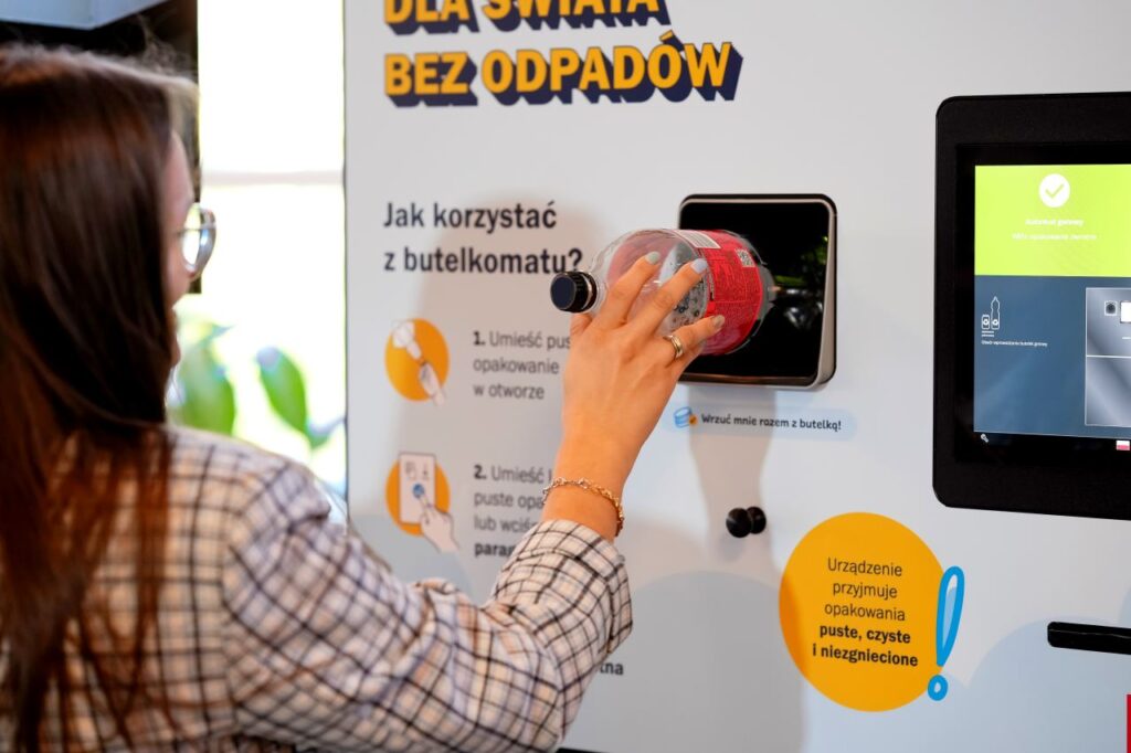 kobieta wkłada pustą plastikową butelkę do otworu w butelkomacie