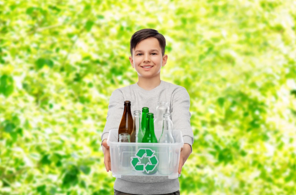 chłopiec trzyma pojemnik z butelkami ze szkła do recyklingu